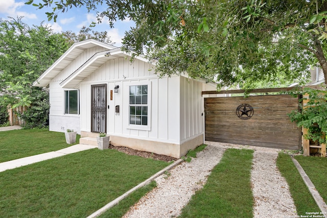 view of front of property featuring a fenced backyard, board and batten siding, driveway, and a front lawn