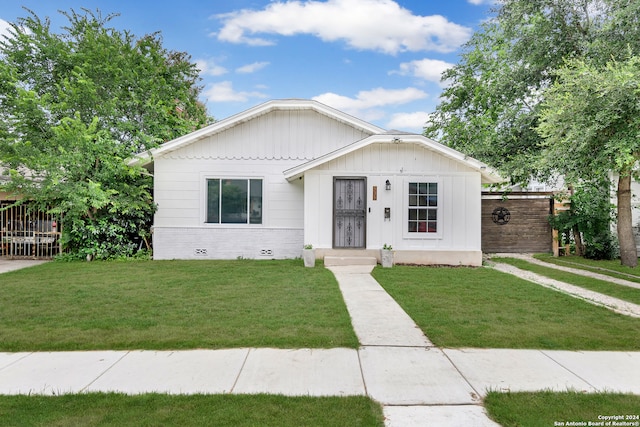 bungalow-style home featuring brick siding, a front yard, and fence