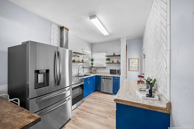 kitchen with open shelves, light wood-style floors, stainless steel appliances, blue cabinets, and a sink