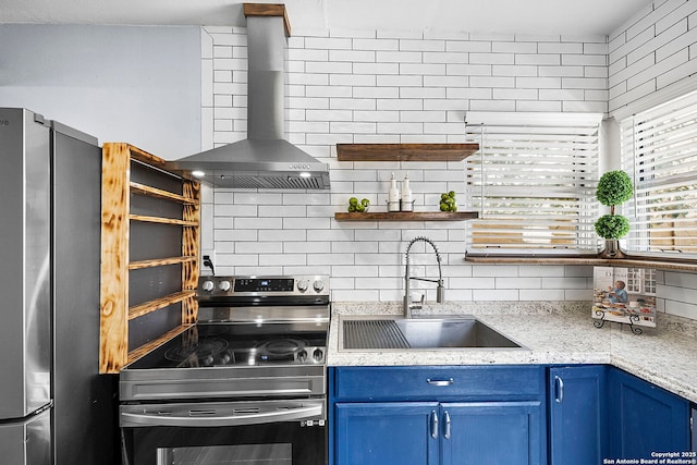 kitchen with blue cabinets, decorative backsplash, stainless steel appliances, wall chimney exhaust hood, and a sink