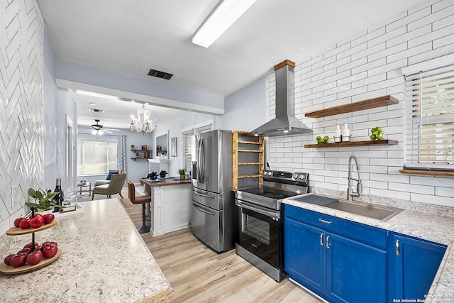 kitchen with blue cabinets, visible vents, a sink, appliances with stainless steel finishes, and wall chimney exhaust hood