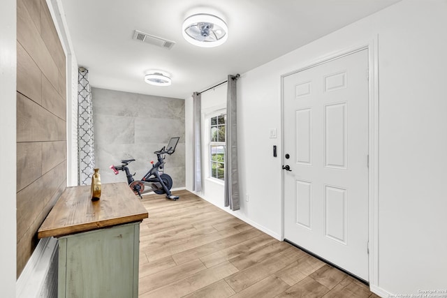 entrance foyer with tile walls, wood finished floors, and visible vents