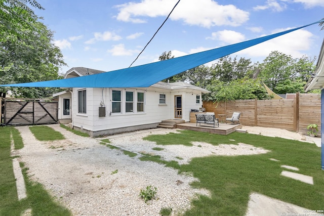 back of house with a gate, fence, a yard, and a wooden deck