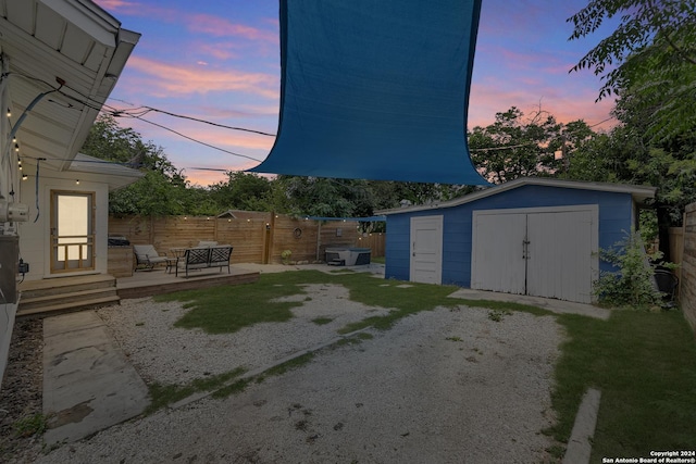 view of yard featuring an outbuilding, a storage shed, a patio, and fence