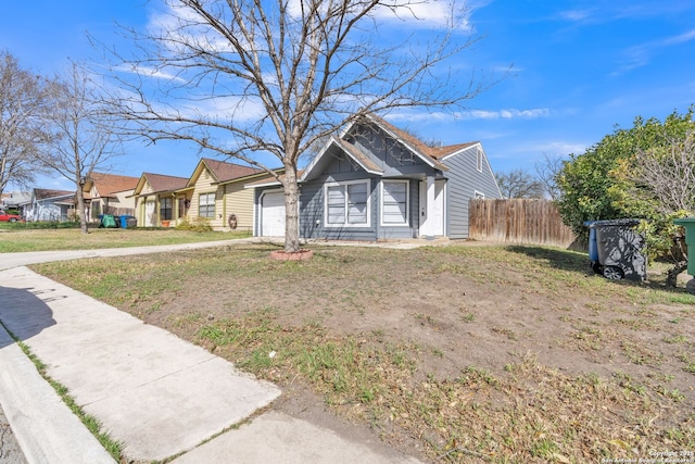 bungalow-style house featuring a front lawn, an attached garage, and fence