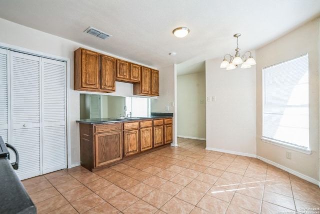 kitchen featuring dark countertops, light tile patterned flooring, visible vents, and brown cabinets