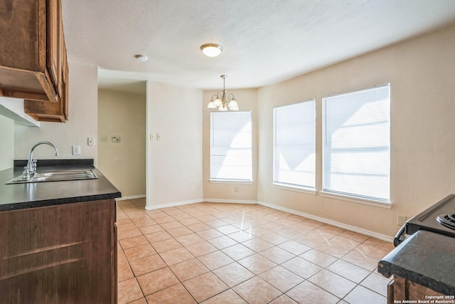 kitchen featuring dark countertops, light tile patterned floors, a notable chandelier, a textured ceiling, and a sink