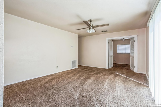 carpeted spare room with visible vents, baseboards, and ceiling fan