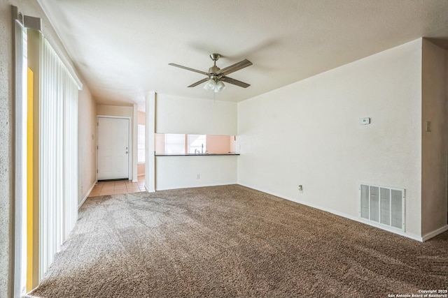 unfurnished living room with visible vents, carpet, and a ceiling fan