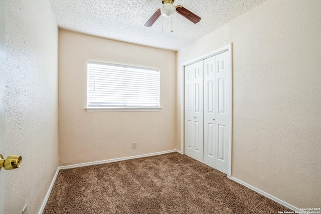 unfurnished bedroom with a ceiling fan, a closet, a textured ceiling, carpet flooring, and a textured wall