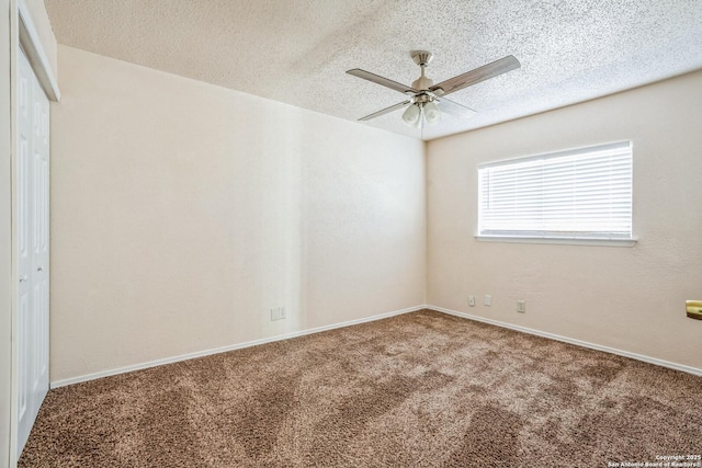 carpeted spare room with baseboards, a textured ceiling, and a ceiling fan