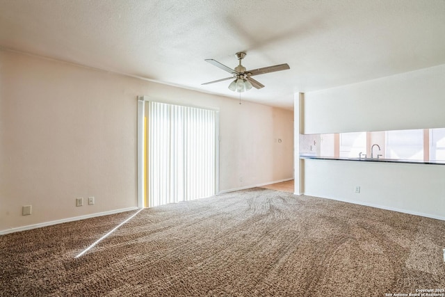 unfurnished living room with baseboards, a textured ceiling, a ceiling fan, and carpet floors