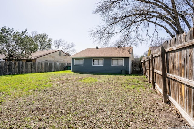 back of house with a yard and a fenced backyard