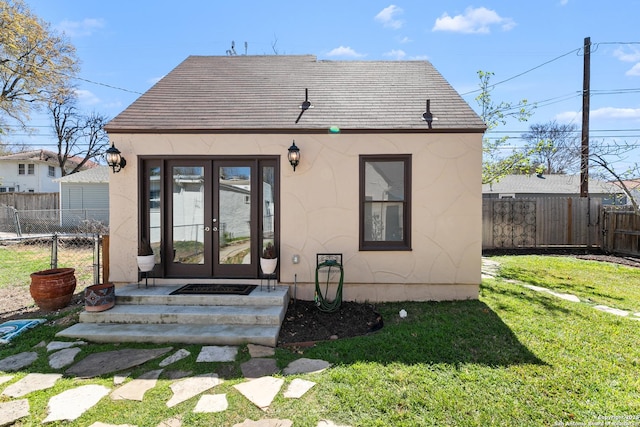 rear view of property with a yard, french doors, fence, and stucco siding