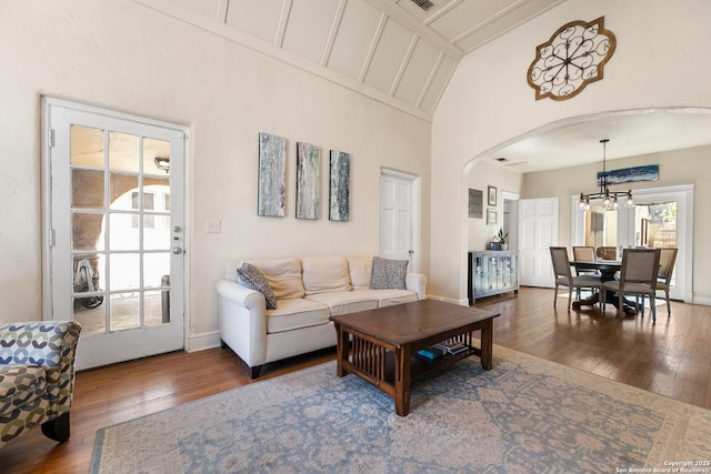 living room featuring baseboards, arched walkways, an inviting chandelier, and hardwood / wood-style floors