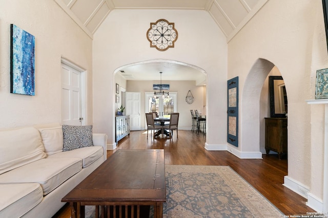 living room featuring arched walkways, a notable chandelier, high vaulted ceiling, and wood finished floors