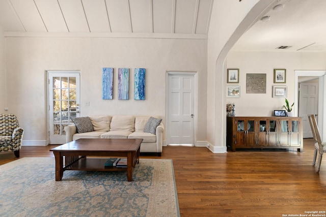 living area featuring visible vents, arched walkways, baseboards, and wood finished floors