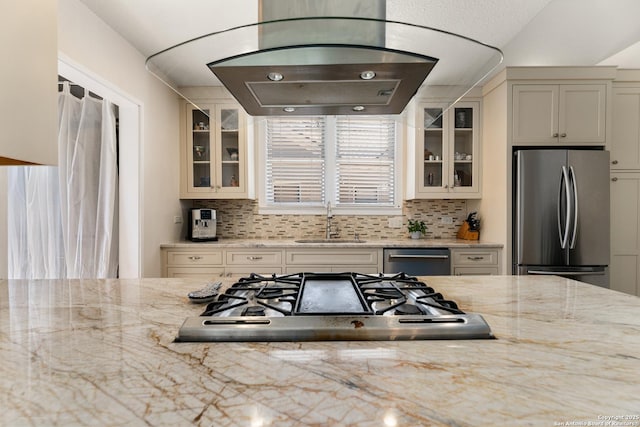 kitchen featuring a sink, light stone counters, glass insert cabinets, and stainless steel appliances