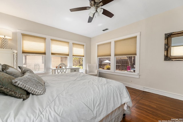 bedroom featuring visible vents, a ceiling fan, baseboards, and wood finished floors