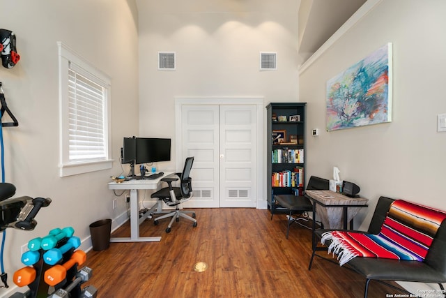 office space with a high ceiling, wood finished floors, and visible vents