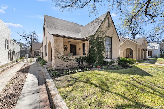 view of front facade featuring stucco siding, driveway, fence, a front yard, and a shingled roof