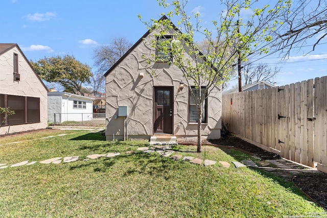 rear view of property featuring a yard, a fenced backyard, and stucco siding