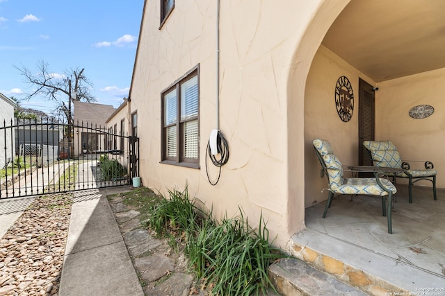 view of side of property with stucco siding and fence