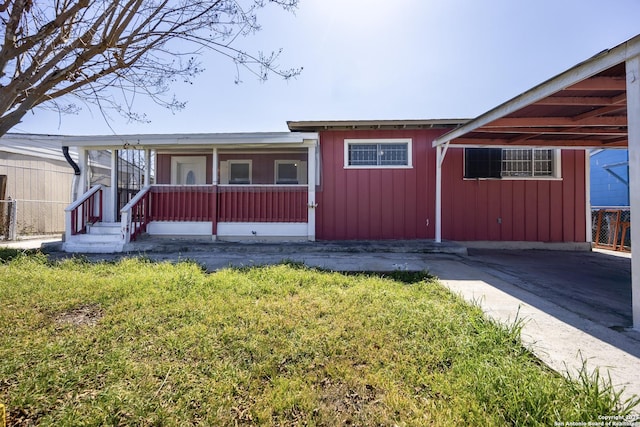 view of front of property with a carport, board and batten siding, and a front lawn