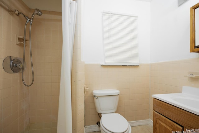 full bath with vanity, toilet, a wainscoted wall, and tiled shower