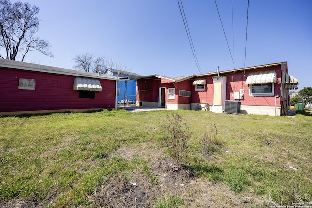 rear view of house with a yard and central AC unit