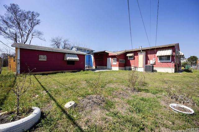 rear view of property featuring a lawn, central AC, and fence