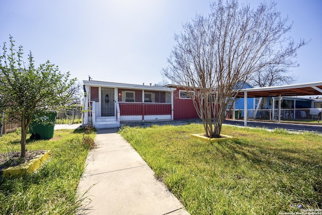 view of front of home with fence, an attached carport, a front lawn, and a sunroom