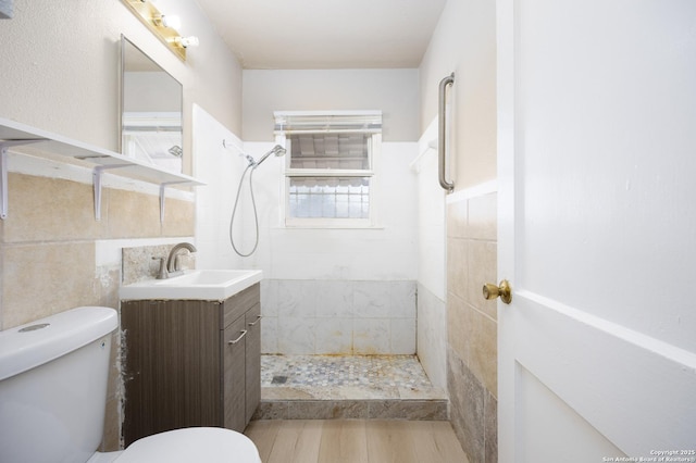 full bath featuring vanity, tile walls, toilet, and tiled shower