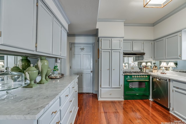 kitchen featuring crown molding, under cabinet range hood, range with two ovens, stainless steel dishwasher, and dark wood-style flooring