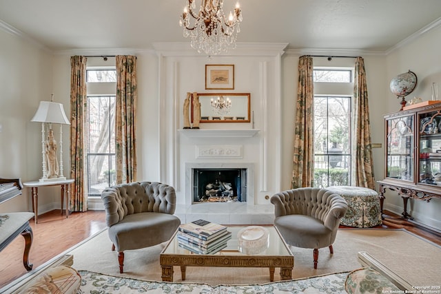 living area with wood finished floors, a tile fireplace, a chandelier, and ornamental molding