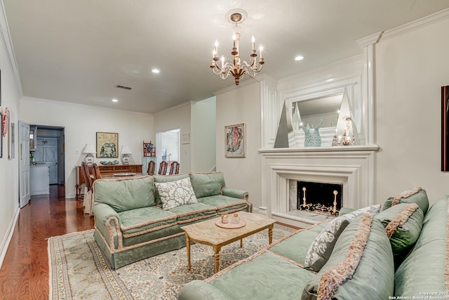 living room with dark wood-type flooring, an inviting chandelier, a fireplace with raised hearth, and crown molding