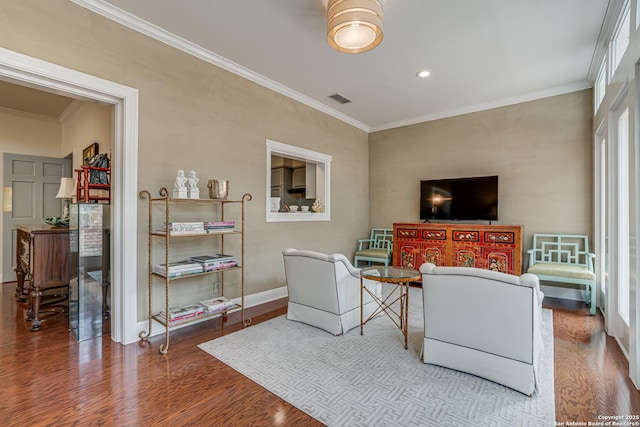 living room featuring visible vents, baseboards, wood finished floors, and ornamental molding