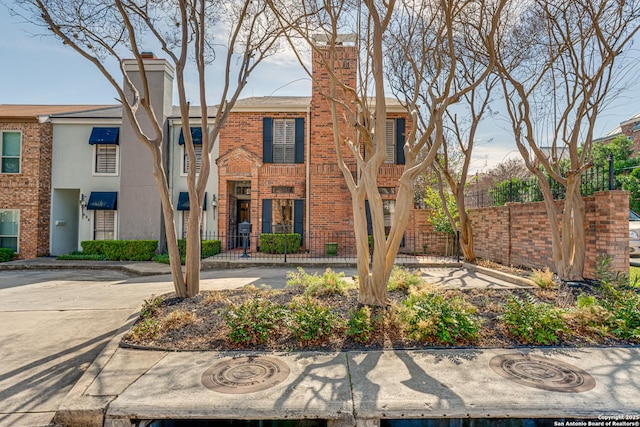 view of property featuring brick siding and fence
