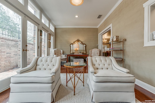 sitting room with wood finished floors, baseboards, visible vents, french doors, and crown molding