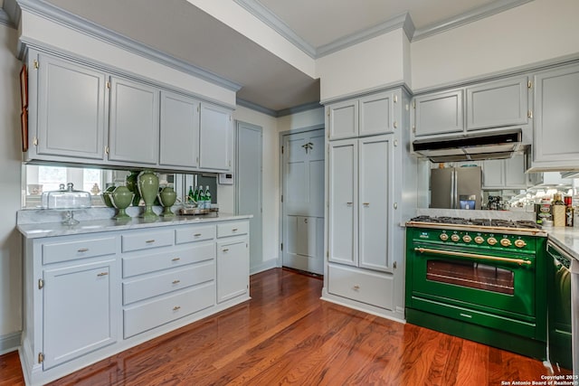 kitchen with ornamental molding, under cabinet range hood, dark wood finished floors, stainless steel fridge, and gas range