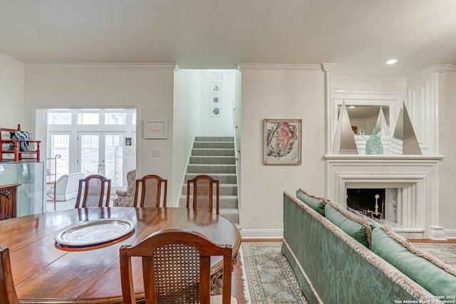 dining space with ornamental molding, stairway, a large fireplace, french doors, and baseboards