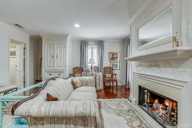 living room featuring visible vents, wood finished floors, ornamental molding, and a tiled fireplace