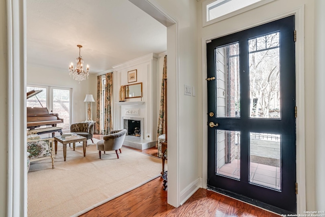 entrance foyer with wood finished floors, baseboards, a fireplace, french doors, and a notable chandelier