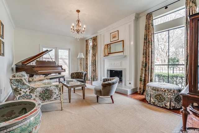 living area with a fireplace with raised hearth, wood finished floors, crown molding, baseboards, and a chandelier