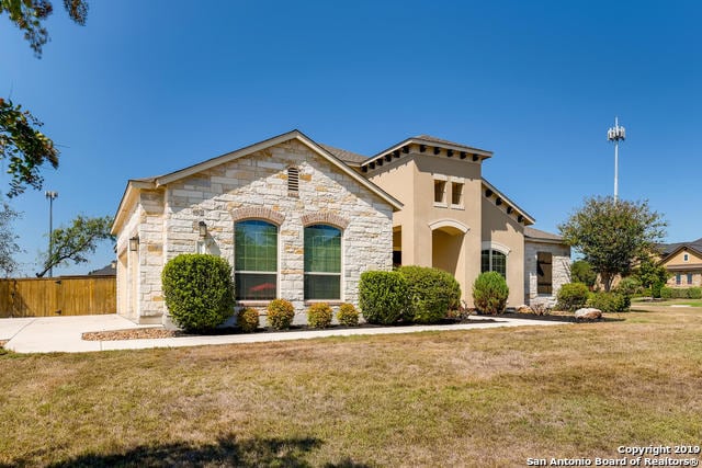 view of front of home with a front lawn, fence, and stone siding