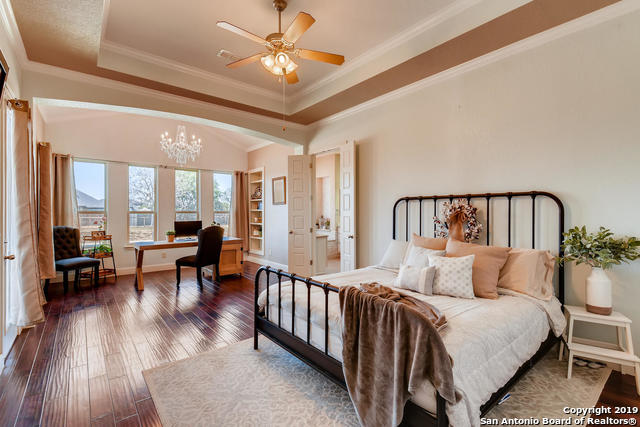 bedroom with a tray ceiling, an inviting chandelier, hardwood / wood-style floors, and crown molding