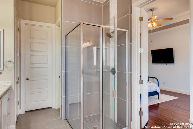 bathroom featuring tile patterned flooring, a stall shower, vanity, and ceiling fan