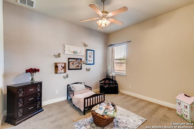 carpeted bedroom with visible vents, baseboards, and ceiling fan