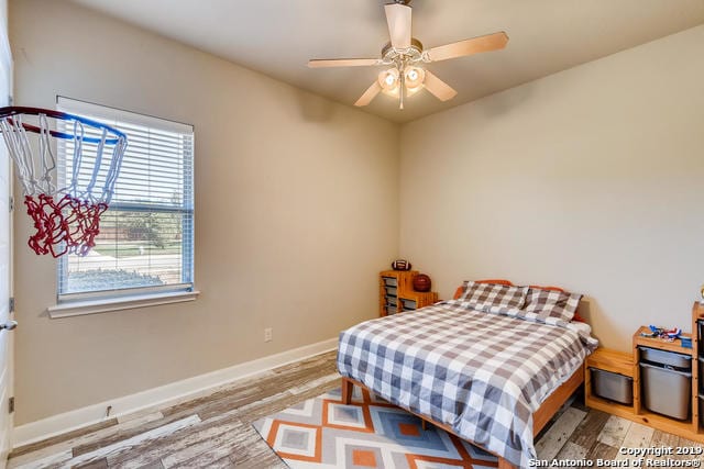 bedroom featuring baseboards, light wood-type flooring, and ceiling fan