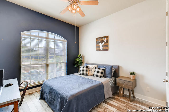 bedroom featuring baseboards, wood finished floors, and a ceiling fan